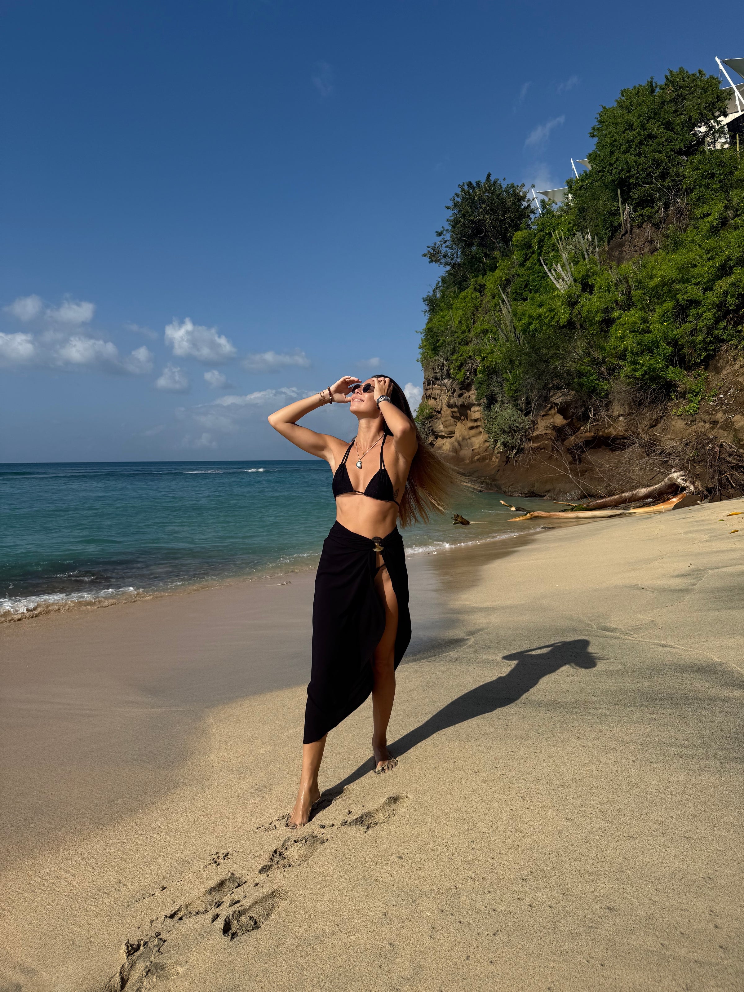 Model in PALM black sarong walking by the ocean